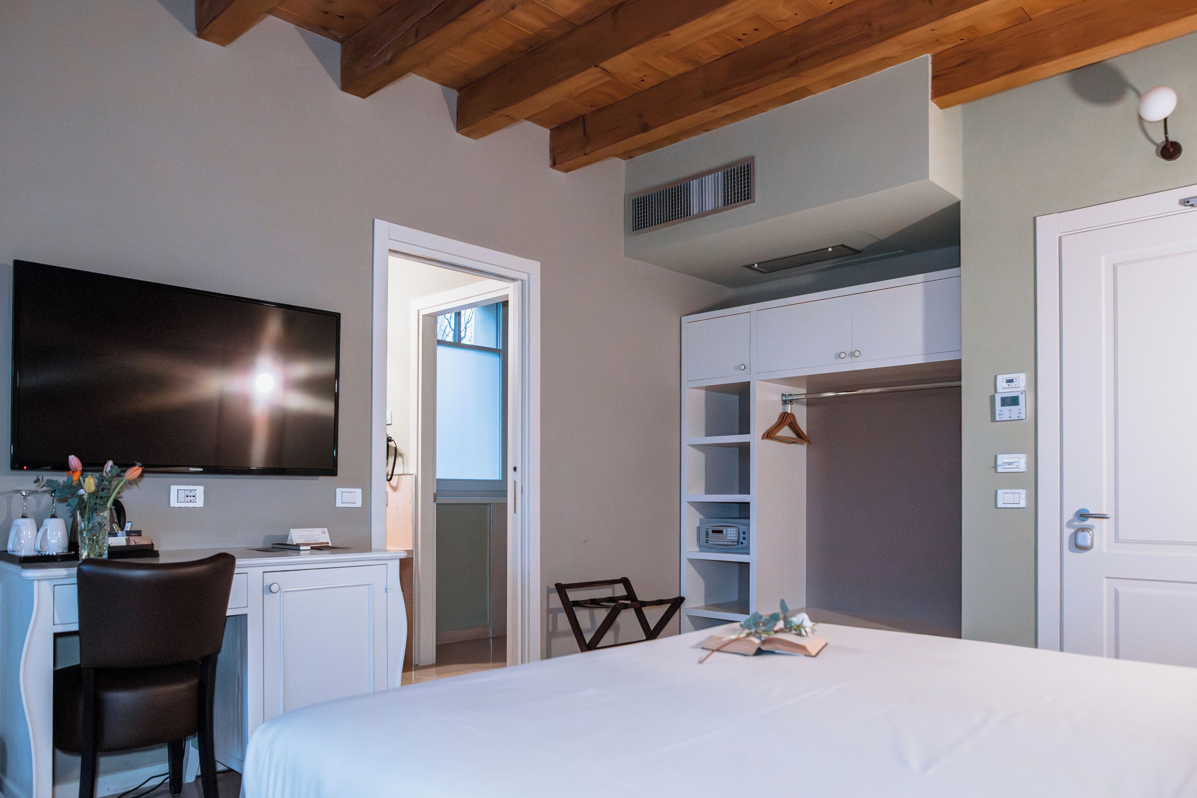 Un dormitorio con cama, escritorio, silla, televisor y armario.