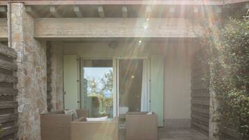 A covered outdoor seating area with wicker furniture and stone walls.