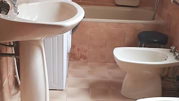 Un baño con lavamanos, bidé, bañera e inodoro.