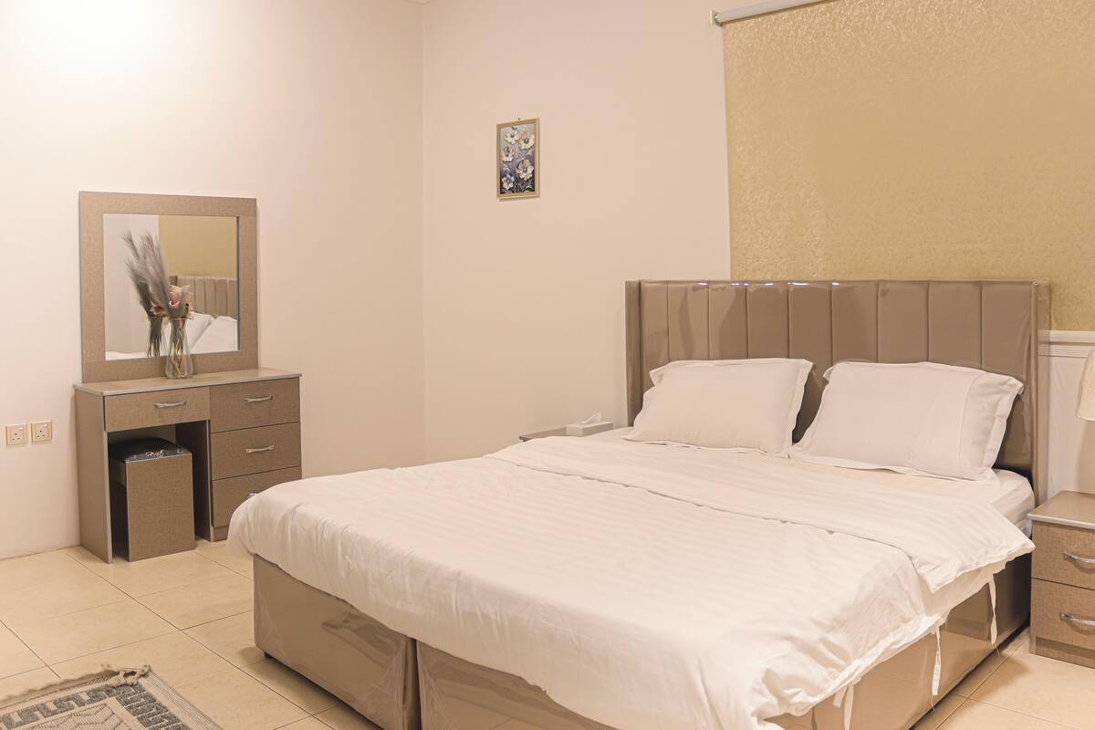 A bedroom with a bed, bedside tables, a dresser, a mirror, and a small decorative item on the dresser.