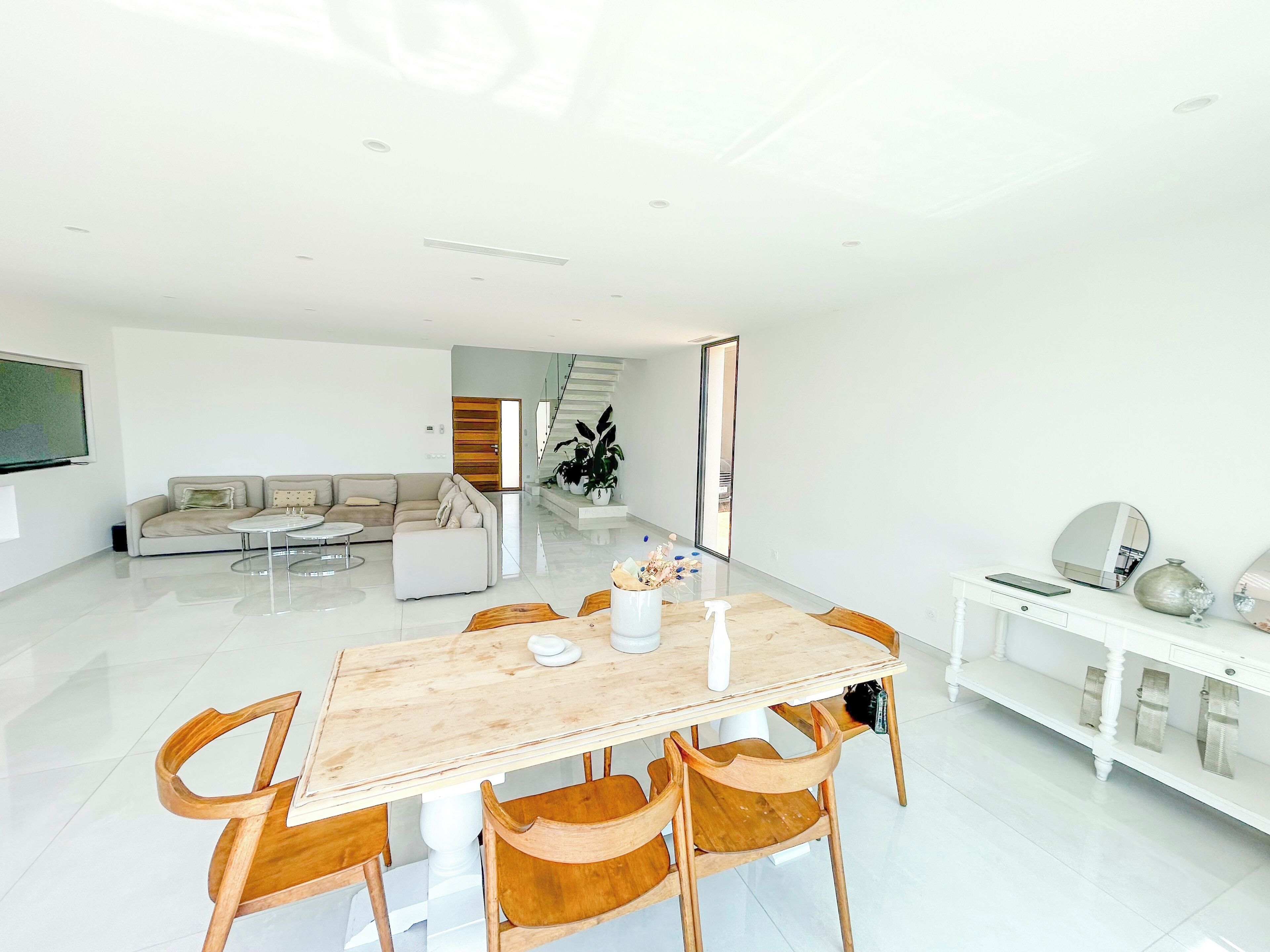 Een moderne woonkamer met een eethoek, een zithoek en een trap naar een ander niveau.