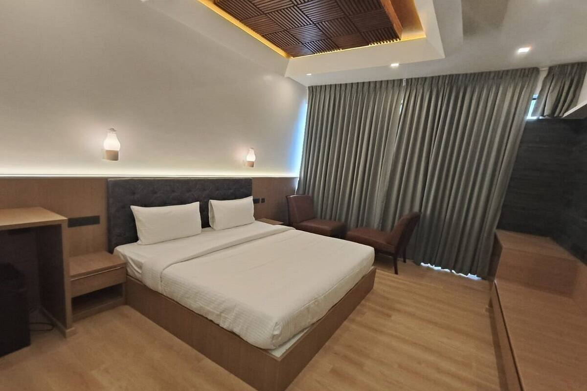 A modern hotel room with a large bed, a desk, and a chair.