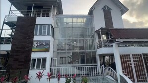 A hotel with a modern design, featuring a glass facade and a sign that reads "Calla Lily." - Calla Lily By The Brook (Kodaikanal)