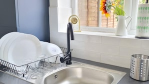 A kitchen sink with a dish rack, a stainless steel faucet, and a window with a view of a garden.