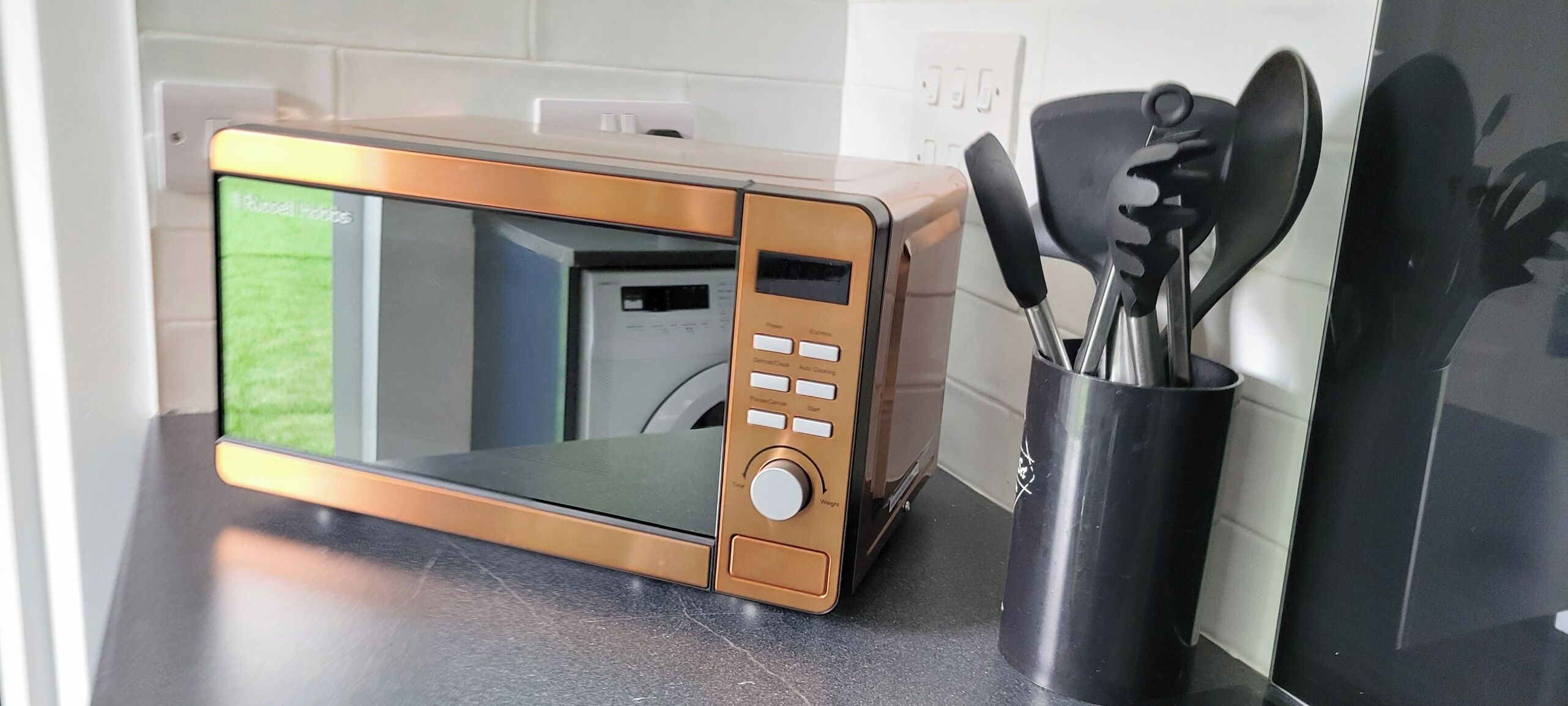 A kitchen with a microwave, a coffee maker, and a utensil holder.