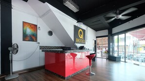 A hotel reception area with a red counter, a painting of a forest path, a clock, and a ceiling fan. - OYO 1104 Q Hotel (Temerloh)