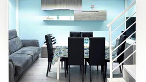 A modern loft apartment with a dining area, a sofa, and a staircase.