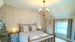 Une chambre à coucher avec un lit à baldaquin, un lustre, une table de chevet avec une lampe et une fenêtre avec des rideaux.