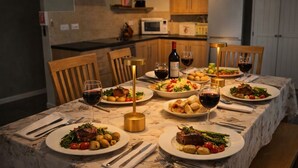 Une table à manger dressée avec des assiettes remplies de nourriture, des verres de vin et une bouteille de vin.