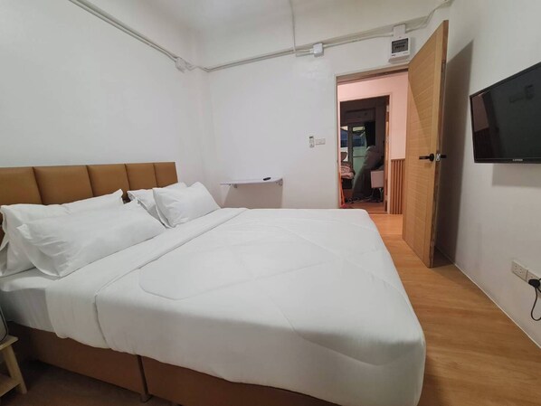 A bedroom with a bed, a nightstand, a TV, and a door leading to another room. - Loft2s.Rangsit (Khlong Luang)