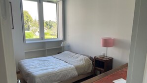 A bedroom with a bed, a nightstand, a lamp, a window, and a desk. - House with character, exceptional view of the river Odet, on one level (Plomelin)