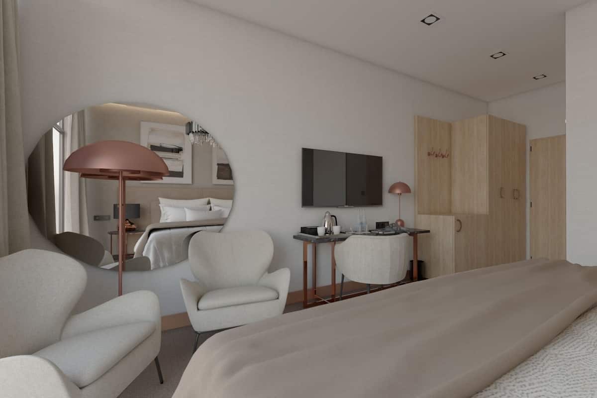 Een moderne hotelkamer met een groot bed, een ronde spiegel, een bureau met lamp, een televisie en een kledingkast.
