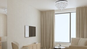 A modern living room with a sofa, armchair, and a coffee table. A flat-screen TV is mounted on the wall, and a chandelier hangs from the ceiling. - Prestige Hotel (Stalowa Wola)