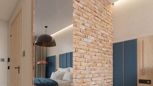 A modern bedroom with a brick accent wall, a bed with blue bedding, and a large mirror. - Prestige Hotel (Stalowa Wola)