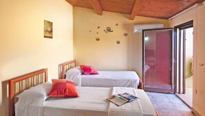 A room with two single beds, a wooden ceiling, a wall with decorative owl stickers, and a sliding glass door. - Casa Plaja (Scicli)