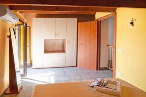 A bedroom with a bed, a wooden wardrobe, and a door leading to another room. - Casa Plaja (Scicli)