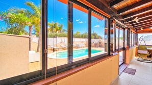 A modern room with large windows, a pool, and outdoor furniture. - Casa Plaja (Scicli)