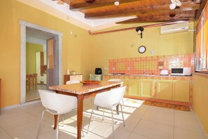 Una cocina con salpicadero de azulejos, microondas, estufa y comedor con mesa y sillas.