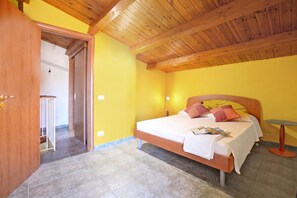 Un dormitorio con techo de madera, una cama con almohadas, una mesita de noche y una pequeña mesa redonda.