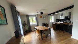 Un salón amplio con una mesa de comedor de madera, una cocina con electrodomésticos modernos y un ventanal que proporciona luz natural.