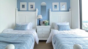 A bedroom with two beds, a dresser, a mirror, and framed pictures on the wall.