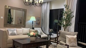 A living room with a sofa, armchair, coffee table, and a chandelier.