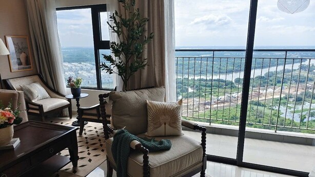 A balcony with a view of a river and greenery. There is a sofa with a cushion and a plant.