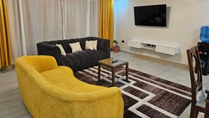 A modern living room with a black sofa, a yellow armchair, and a coffee table.