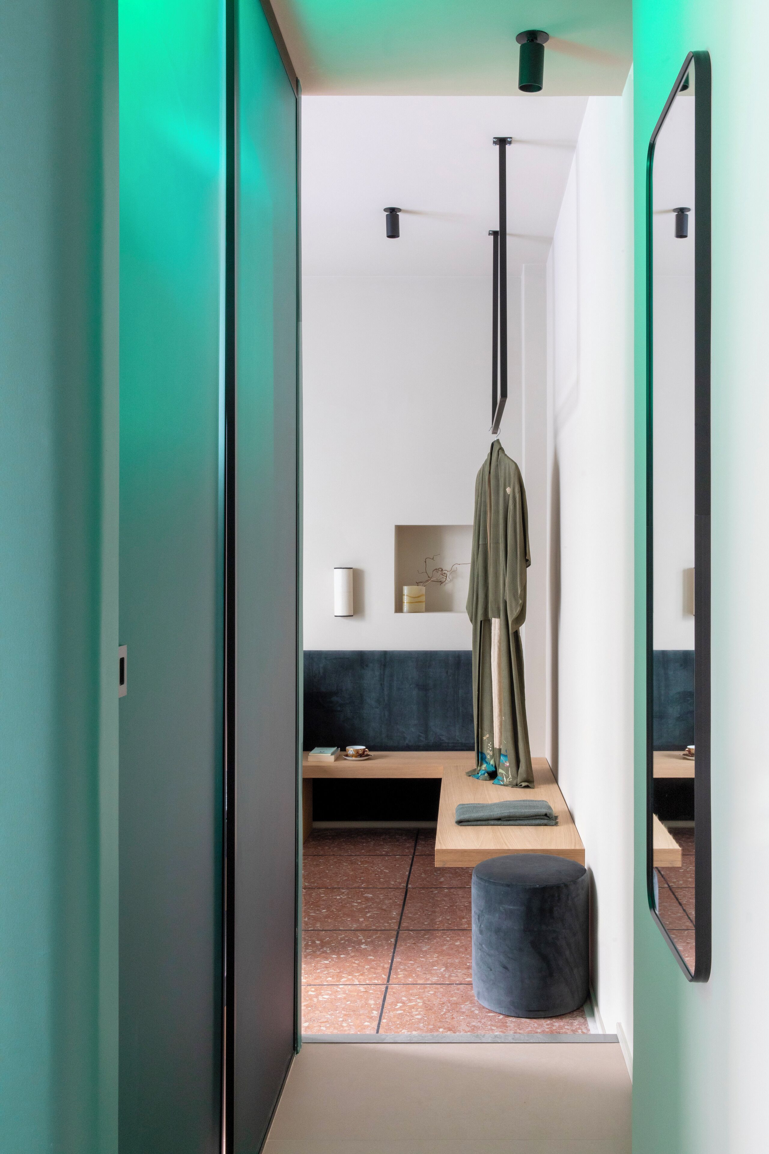 Een moderne badkamer met een handdoekrek, een spiegel en een plank met een handdoek en een klein decoratief object.
