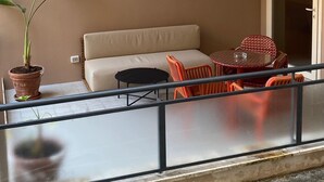 A balcony with a beige sofa, a small round table, and a potted plant. - Atel Relais (Rome)