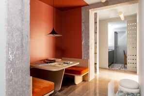 A modern room with a wooden desk, orange cushions, and a hanging pendant light. - Atel Relais (Rome)