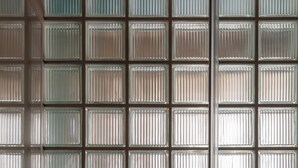 A wall with a grid of square panels, some with vertical ridges. - Atel Relais (Rome)