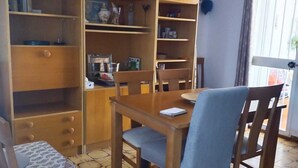 A dining area with a wooden table and chairs, surrounded by wooden bookshelves filled with books and decorative items. - Beautiful house 30 meters from the sea (Almonte)