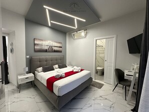 A modern bedroom with a large bed, a desk, and a shower. - Sweet Tide Suites (Licata)