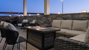 Un patio al aire libre con paredes de piedra, muebles de mimbre y una chimenea.