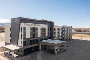 A modern Hyatt Place hotel with a prominent entrance, large windows, and a covered outdoor seating area.