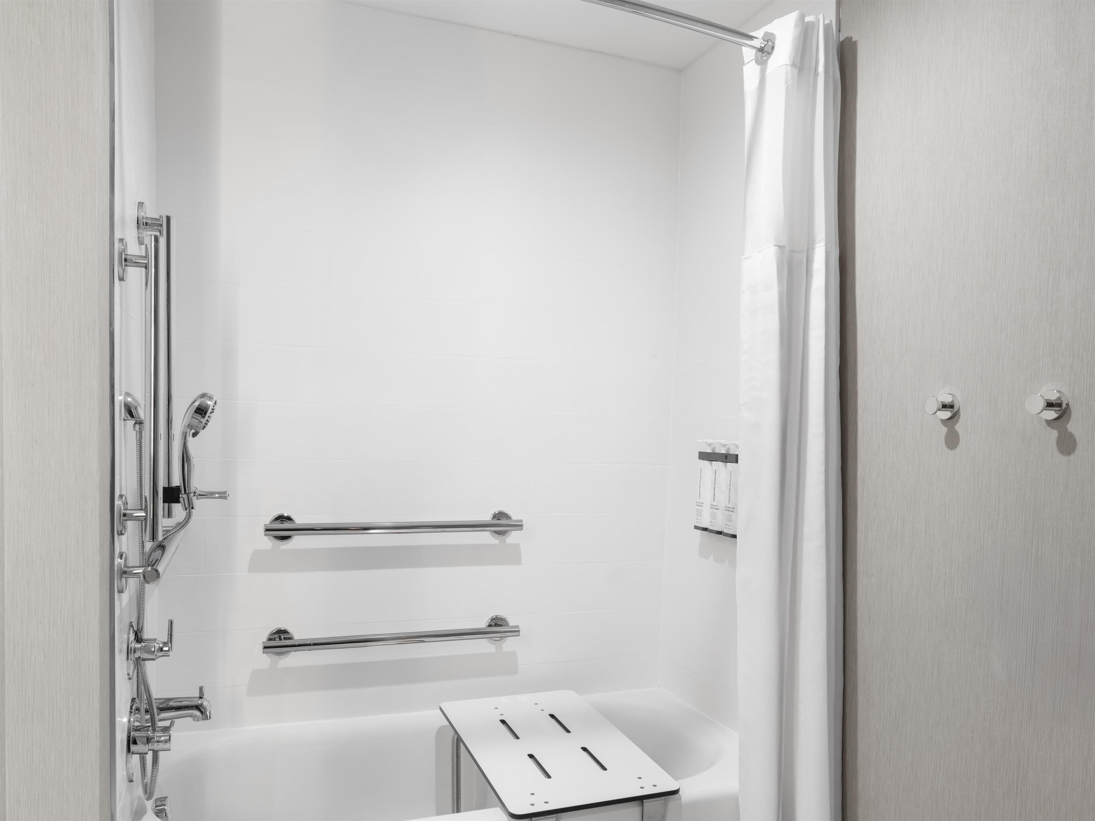 Een moderne douchecel met een glazen deur, chroombeslag en een witte betegelde wand.