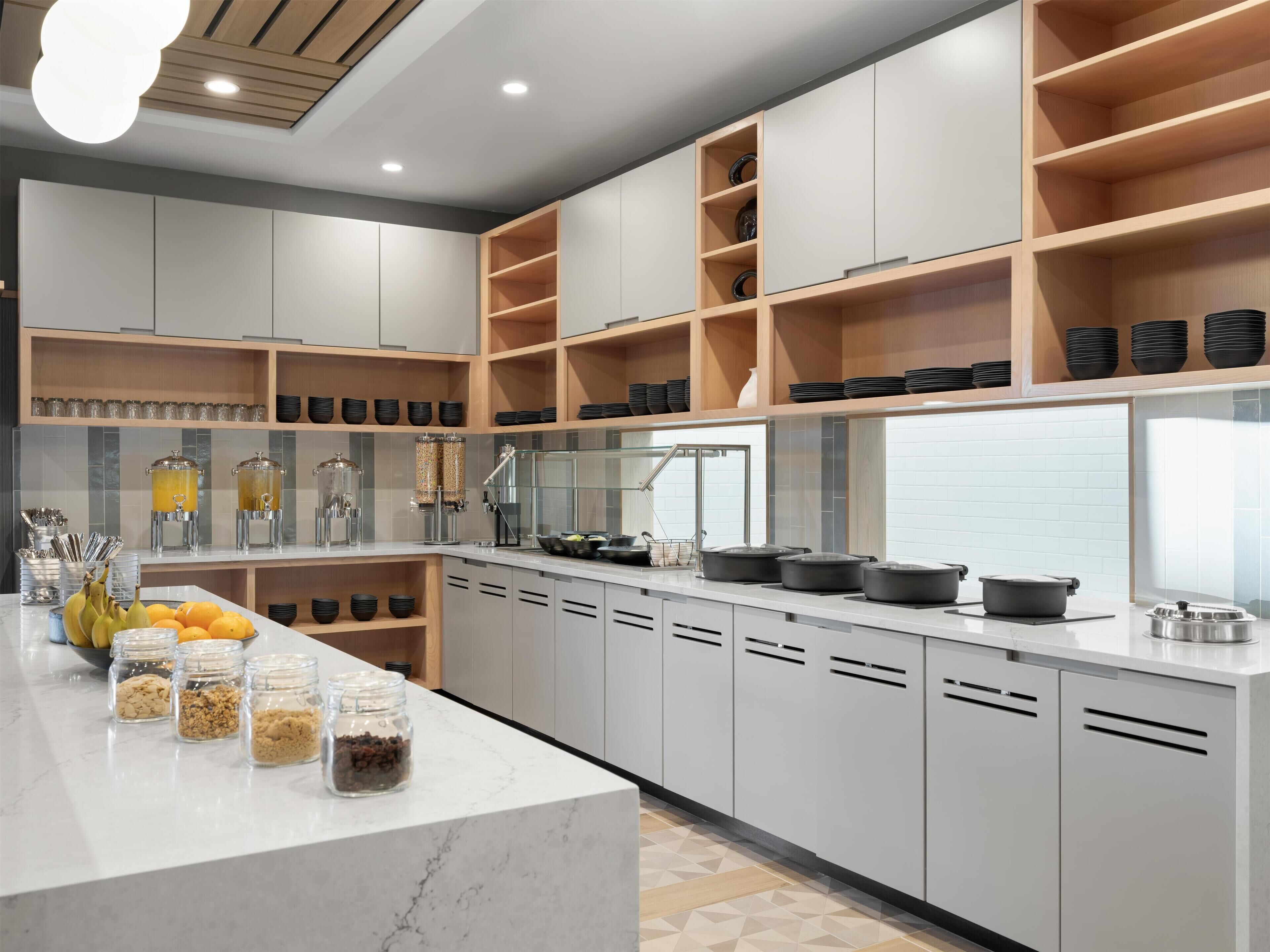 Una cocina moderna con armarios blancos, repisas de madera y encimera de mármol.