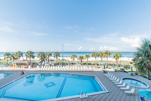 A pool area with lounge chairs and a view of the beach.