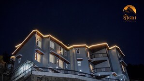 A multi-story building with a modern architectural design, featuring balconies and a prominent roofline. - Dogri Homes (Shimla)