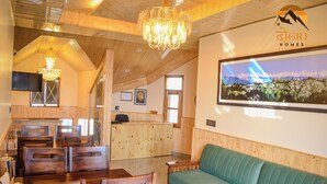 A wooden interior with a reception desk, seating area, and a chandelier. - Dogri Homes (Shimla)