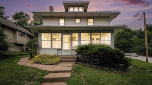 A two-story house with a front porch, large windows, and a well-maintained lawn.