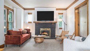 A living room with a fireplace, a television mounted above it, and a sofa.
