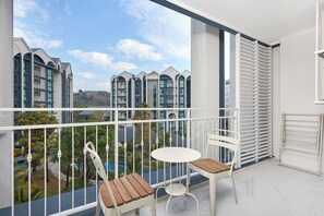 A balcony with white metal railings, a white table, and two white chairs with wooden seats. - The Title Halo NaiYang by My Home Phuket (Thep Krasattri)