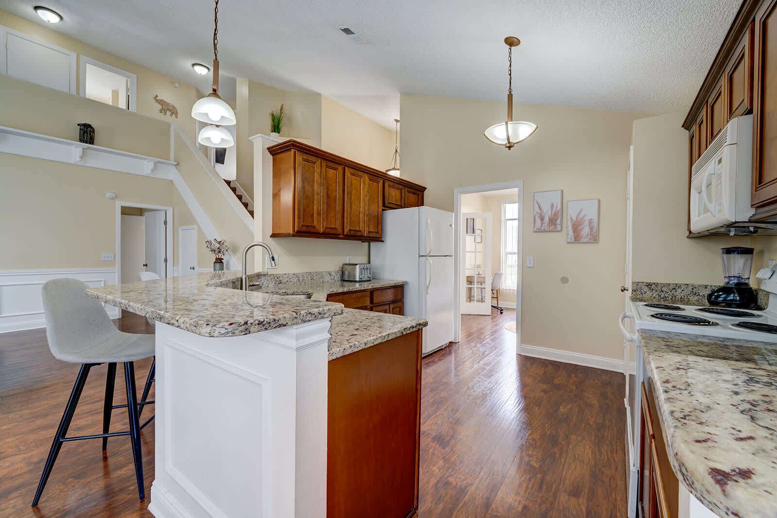Modern kitchen with granite countertops and warm wood cabinetry overlooking the open living area.