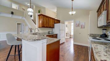 Modern kitchen with granite countertops and warm wood cabinetry overlooking the open living area.