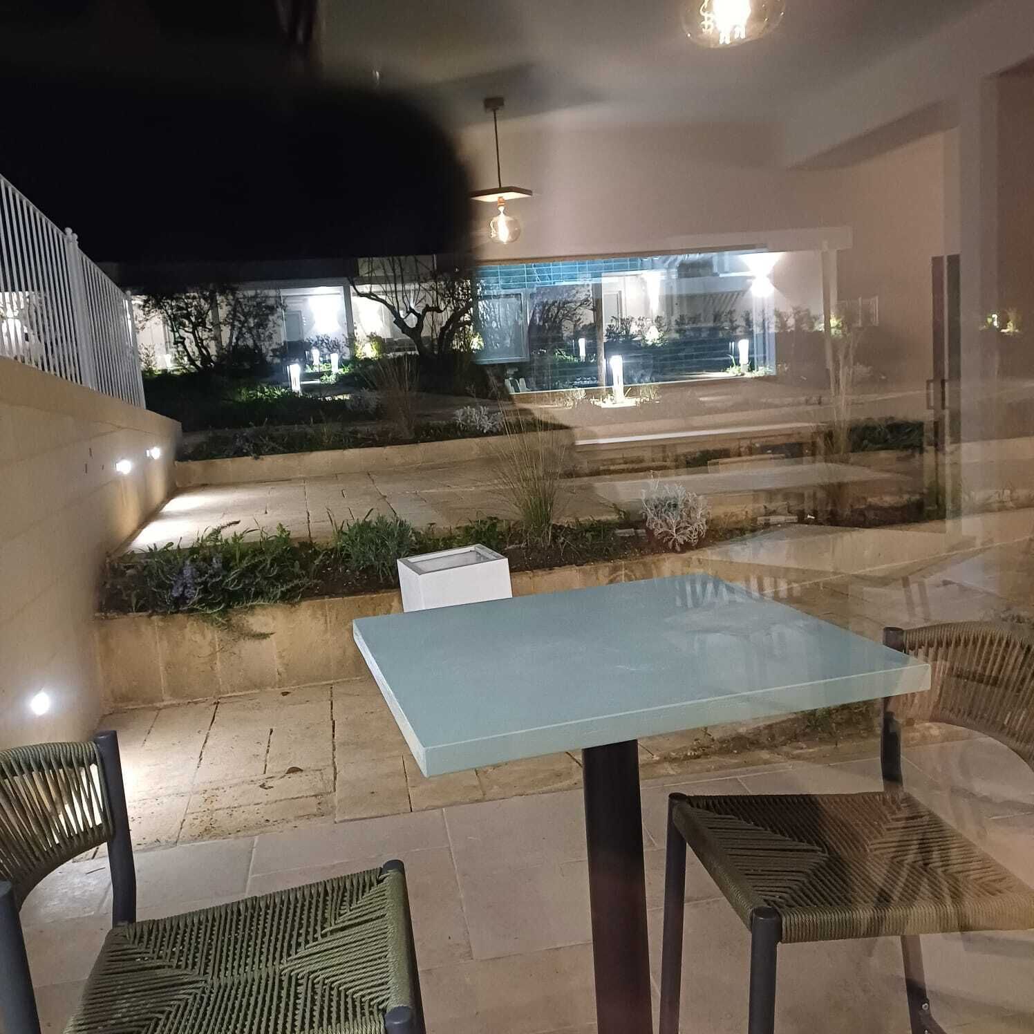 An outdoor seating area with a table and chairs, a staircase, and a view of a lit building in the background.