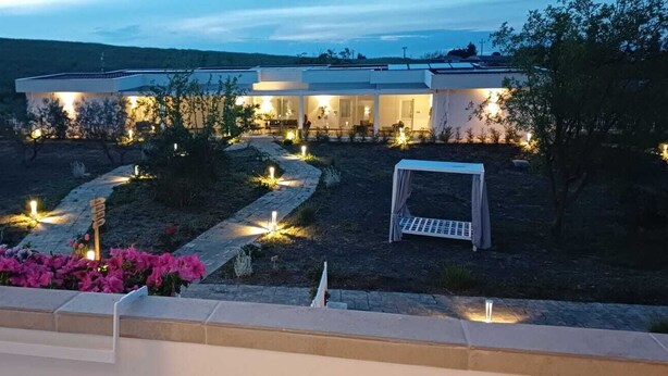 A modern building with a well-lit outdoor area, including a pathway and seating areas. - amarena garden house (Matera)