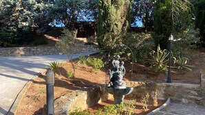 Un camino de piedra que lleva a un jardín con una estatua y una fuente.