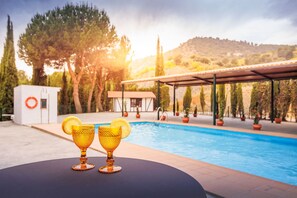 A poolside setting with two golden goblets on a table, surrounded by potted plants and a pool.